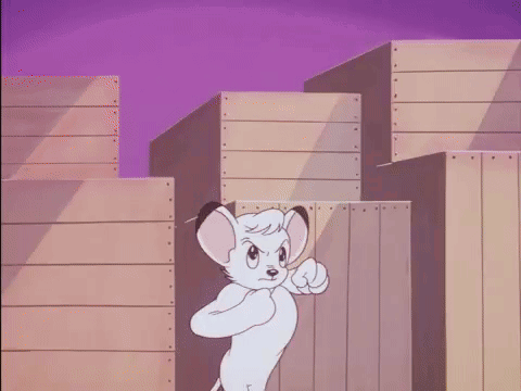 A Cartoon Lion Is Standing In Front Of A Wooden Fence And Pointing At The Camera . GIF