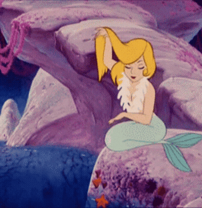 A Cartoon Mermaid Is Sitting On A Rock In The Ocean GIF