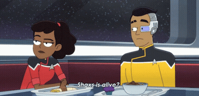 A Cartoon Of A Man And A Woman Sitting At A Table With The Man Saying Shax Is Alive GIF
