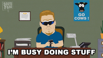 A Cartoon Of A Man Sitting At A Desk With The Words I 'M Busy Doing Stuff Above Him GIF