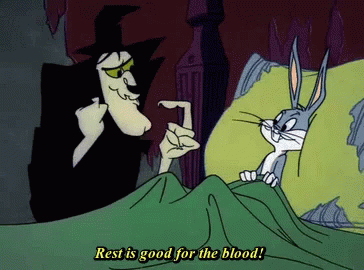 A Cartoon Of A Witch Talking To Bugs Bunny Who Is Laying In Bed GIF