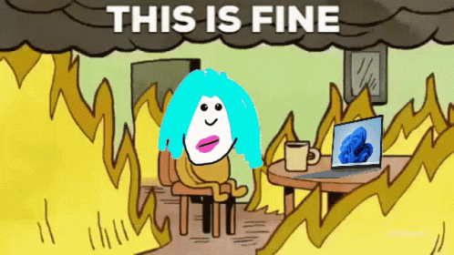 A Cartoon Of A Woman Sitting At A Table With A Laptop And A Cup Of Coffee Under A Cloud That Says This Is Fine GIF