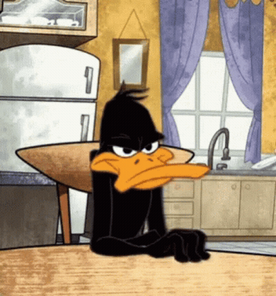 A Cartoon Of Daffy Duck Sitting At A Kitchen Table GIF