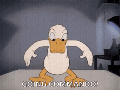 A Cartoon Of Donald Duck Standing On A Table With The Words `` Going Commando '' Written Below Him . GIF