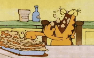 A Cartoon Of Garfield Eating A Lasagna On A Table . GIF