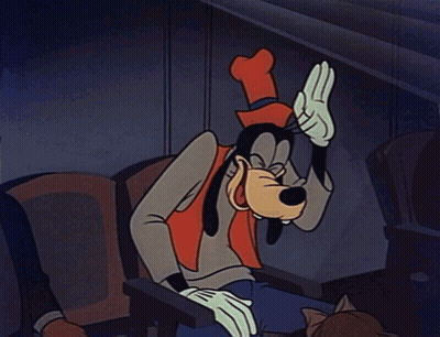 A Cartoon Of Goofy Sitting In A Chair With His Hand On His Head GIF