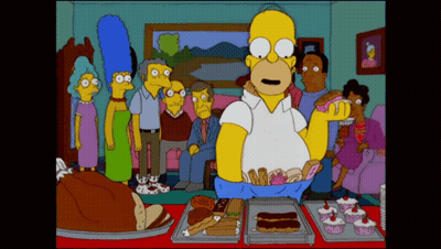 A Cartoon Of Homer Simpson Standing In Front Of A Table Full Of Desserts GIF