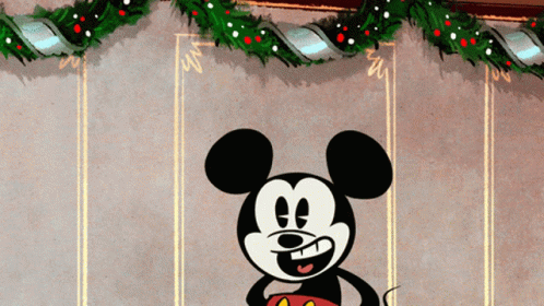 A Cartoon Of Mickey Mouse Standing In Front Of A Christmas Wreath GIF