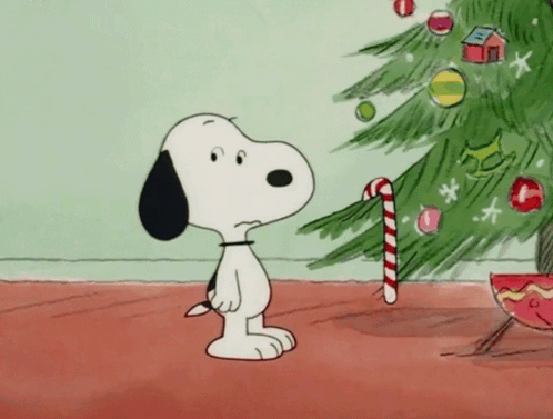 A Cartoon Of Snoopy Holding A Candy Cane Standing Next To A Christmas Tree GIF