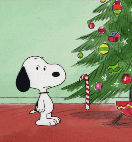 A Cartoon Of Snoopy Standing Next To A Christmas Tree With A Candy Cane GIF