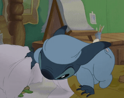 A Cartoon Of Stitch Laying On A Bed With A Frog Behind Him GIF