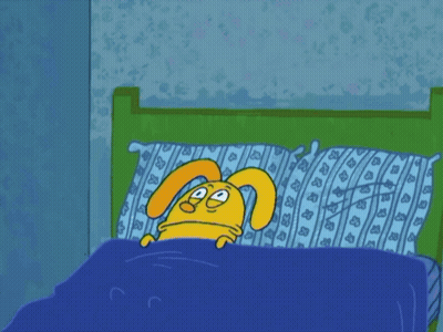 A Cartoon Rabbit Is Laying In A Bed With A Blue Blanket GIF
