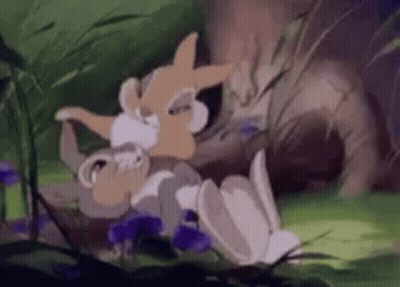 A Cartoon Rabbit Is Laying On The Ground In The Grass . GIF