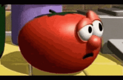 A Cartoon Tomato With Big Eyes And A Nose Is Standing On A Yellow Table . GIF