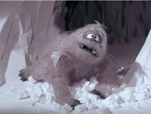 A Cartoon Yeti Is Laying In The Snow And Looking At The Camera GIF