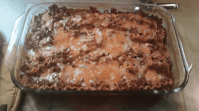 A Casserole Dish Filled With Lasagna And Cheese GIF