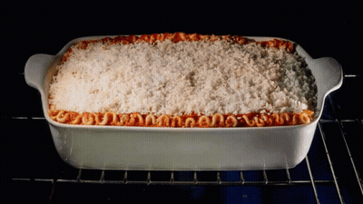A Casserole Dish Filled With Macaroni And Cheese Is Being Cooked In An Oven GIF