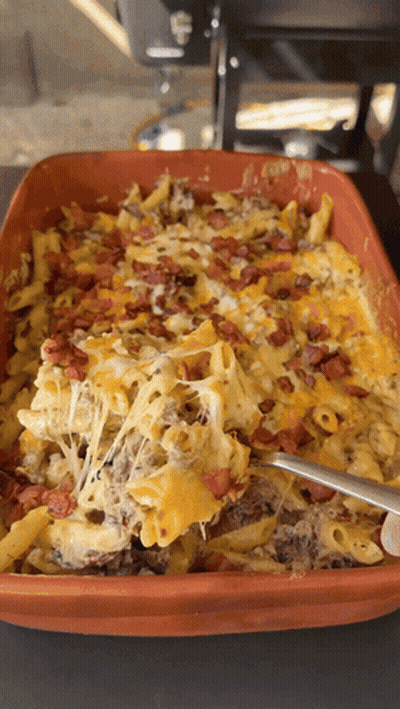 A Casserole Dish Filled With Macaroni Cheese Bacon And A Spoon GIF