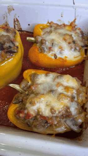 A Casserole Dish Filled With Stuffed Peppers Covered In Sauce And Cheese GIF