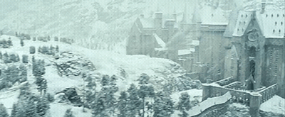 A Castle Is Surrounded By Snow Covered Trees And Mountains GIF