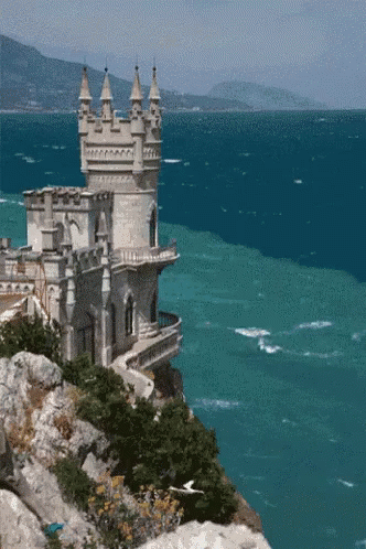 A Castle Sits On Top Of A Rock Overlooking The Ocean GIF