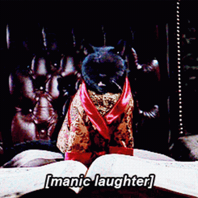 A Cat In A Robe Is Sitting On A Bed With The Words [ Manic Laughter ] Written Above It GIF