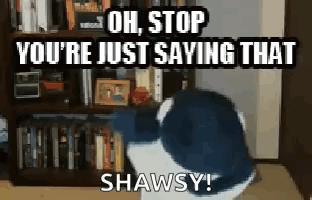 A Cat Is Sitting In Front Of A Bookshelf And Says Oh Stop You 'Re Just Saying That Shawsy . GIF