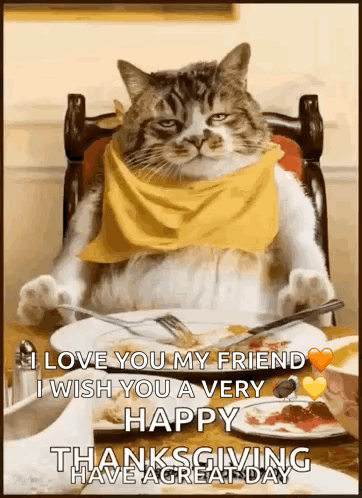 A Cat Wearing A Yellow Scarf Is Sitting At A Table With A Plate Of Food And A Fork . GIF