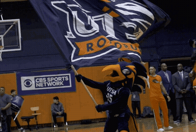 A Cbs Sports Network Ad Is Behind A Mascot Holding A Flag GIF