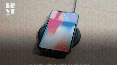 A Cell Phone Sitting On A Charger With The Time 9:23 On The Screen GIF