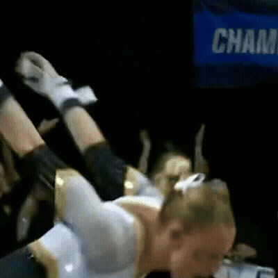 A Cheerleader Is Laying On Her Back In Front Of A Sign That Says Champ GIF