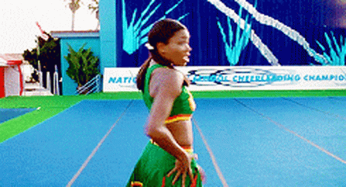 A Cheerleader Is Standing In Front Of A Sign That Says ' National Cheerleading Champion ' GIF