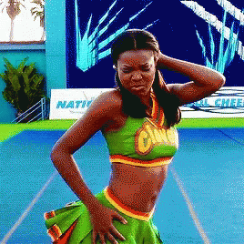 A Cheerleader Stands In Front Of A Sign That Says Nation On It GIF
