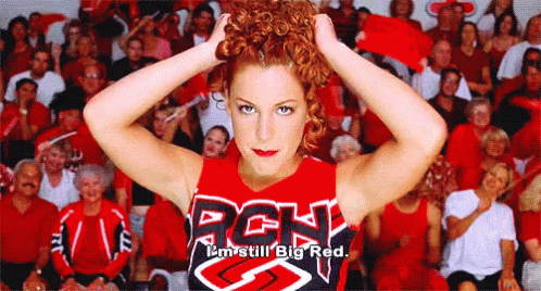 A Cheerleader Wearing A Rgh Shirt Is Standing In Front Of A Crowd GIF