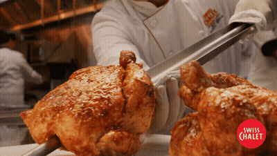 A Chef Is Cutting A Piece Of Roasted Chicken With Tongs From A Swiss Chalet Restaurant GIF