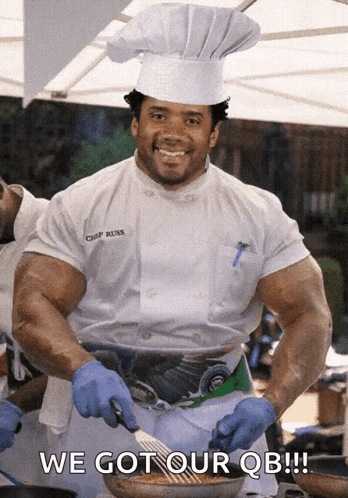 A Chef With Huge Muscles Is Smiling And Holding A Spatula In Front Of A Sign That Says We Got Our Qb GIF