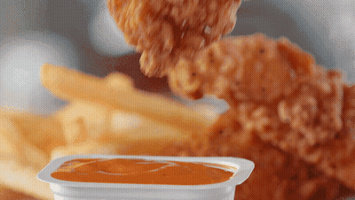 A Chicken Nugget Is Being Dipped Into A Container Of Sauce GIF