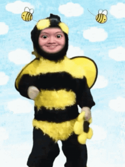 A Child Dressed In A Bee Costume With Two Bees Flying Around His Head GIF