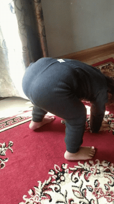 A Child Is Bending Over On A Red Rug GIF