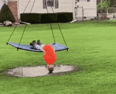A Child Is Doing A Handstand On A Hammock In A Yard GIF