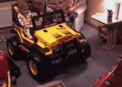 A Child Is Driving A Yellow Toy Jeep In A Room . GIF
