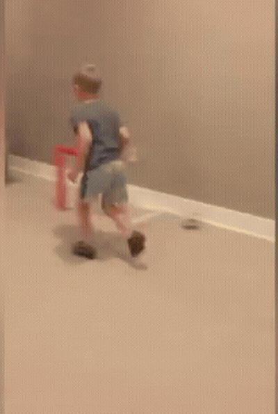 A Child Is Jumping In The Air Near A Basketball Hoop In A Room GIF