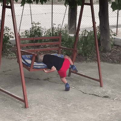 A Child Is Laying On A Wooden Swing With A Blue And White Blanket GIF