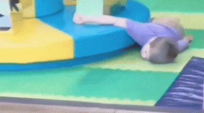 A Child Is Laying On The Floor In A Playground GIF