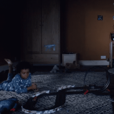 A Child Is Laying On The Floor Playing With A Toy Track GIF