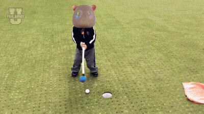 A Child Is Laying On The Grass With A Flag In Front Of A Golf Ball GIF