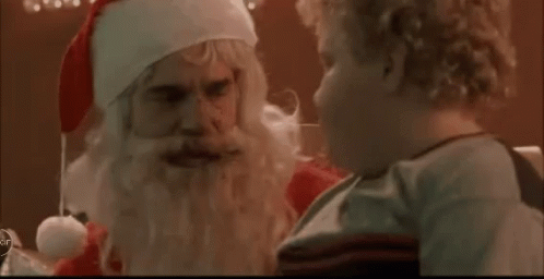A Child Is Talking To Santa Claus Who Is Wearing A Santa Hat . GIF