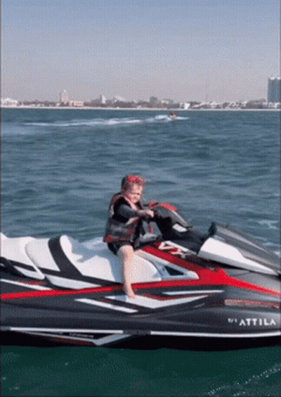 A Child Sits On A Jet Ski That Says " Attimo " On The Side GIF