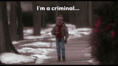 A Child Walking Down A Snowy Sidewalk With The Words " I 'M A Criminal " Behind Him GIF