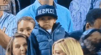 A Child Wearing A Hat That Says Respect Is Sitting In A Crowd Of People . GIF